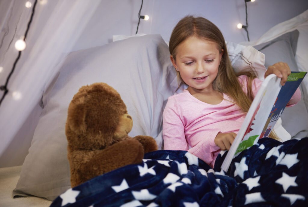 Niña leyendo un cuento infantil impreso en tapa blanda