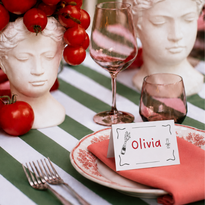 Marcasitio plegado personalizado modelo Olivia Mediterráneo sobre plato con servilleta coral en mesa de boda al aire libre