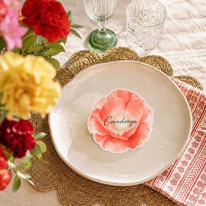 Marcasitio personalizado con forma de amapola sobre plato en mesa de boda con flores