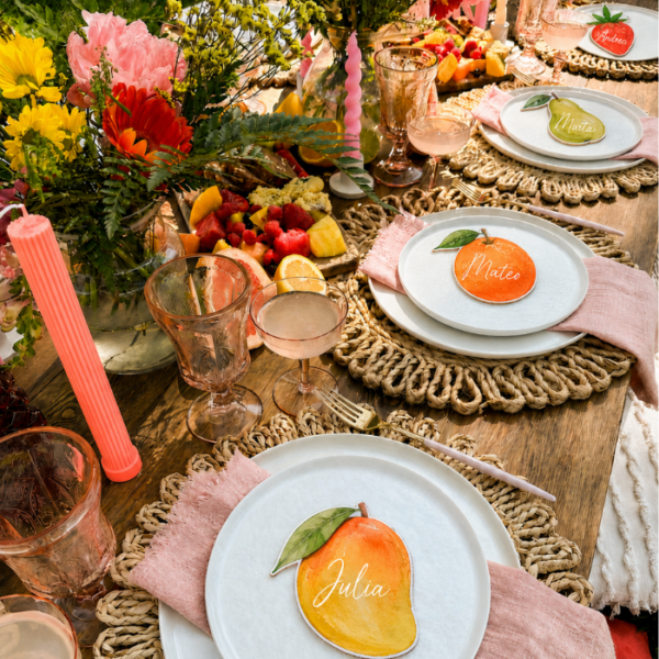 Marcasitios troquelados con forma de frutas sobre platos en mesa de boda decorada