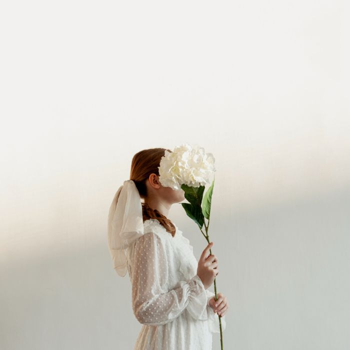 ovia con vestido blanco plumeti sosteniendo una hortensia blanca