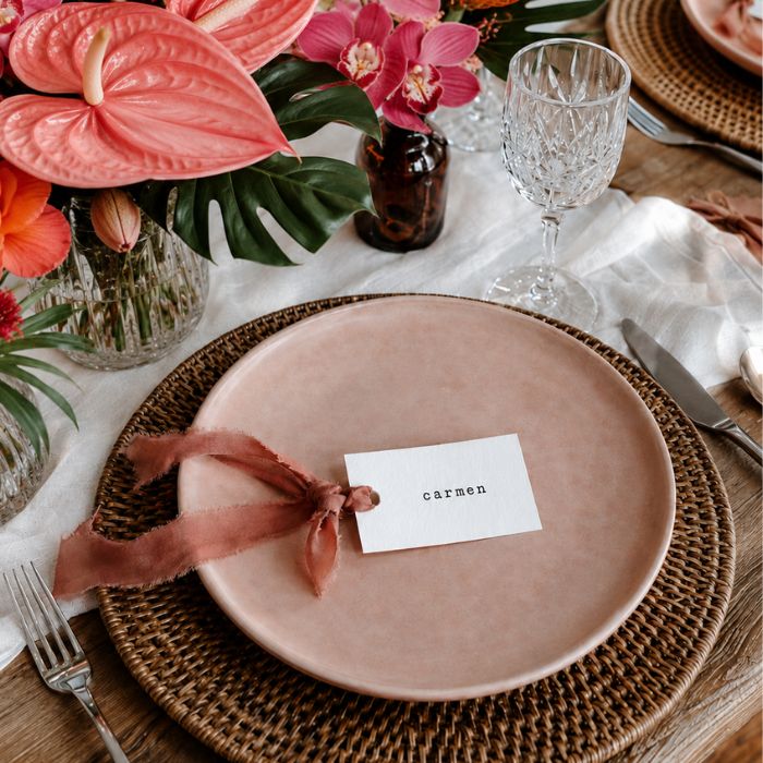 Marcasitios boda personalizados etiqueta con cinta terracota sobre mesa de boda tropical